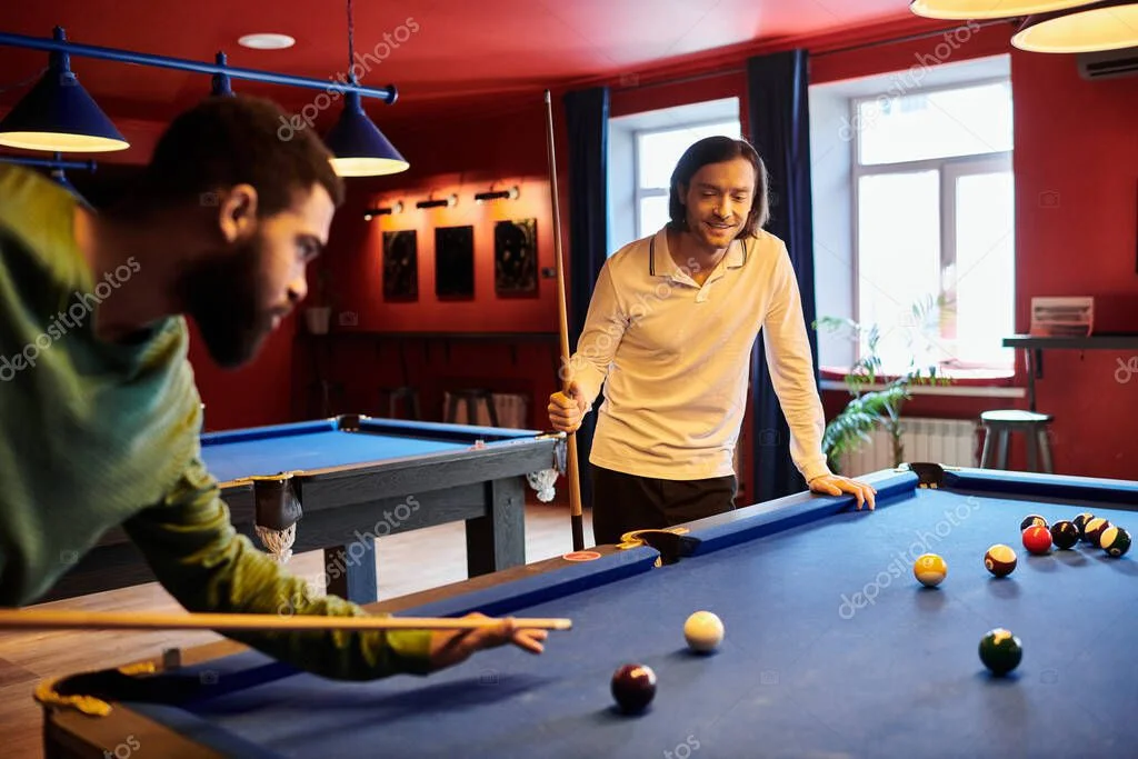 Snooker tables in the games room with players lining up a shot